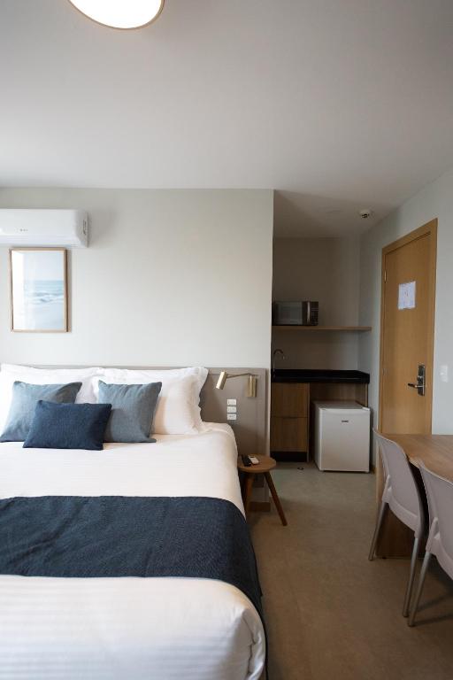 a bedroom with a large bed and a table at Luísa Studio Hotel in Florianópolis
