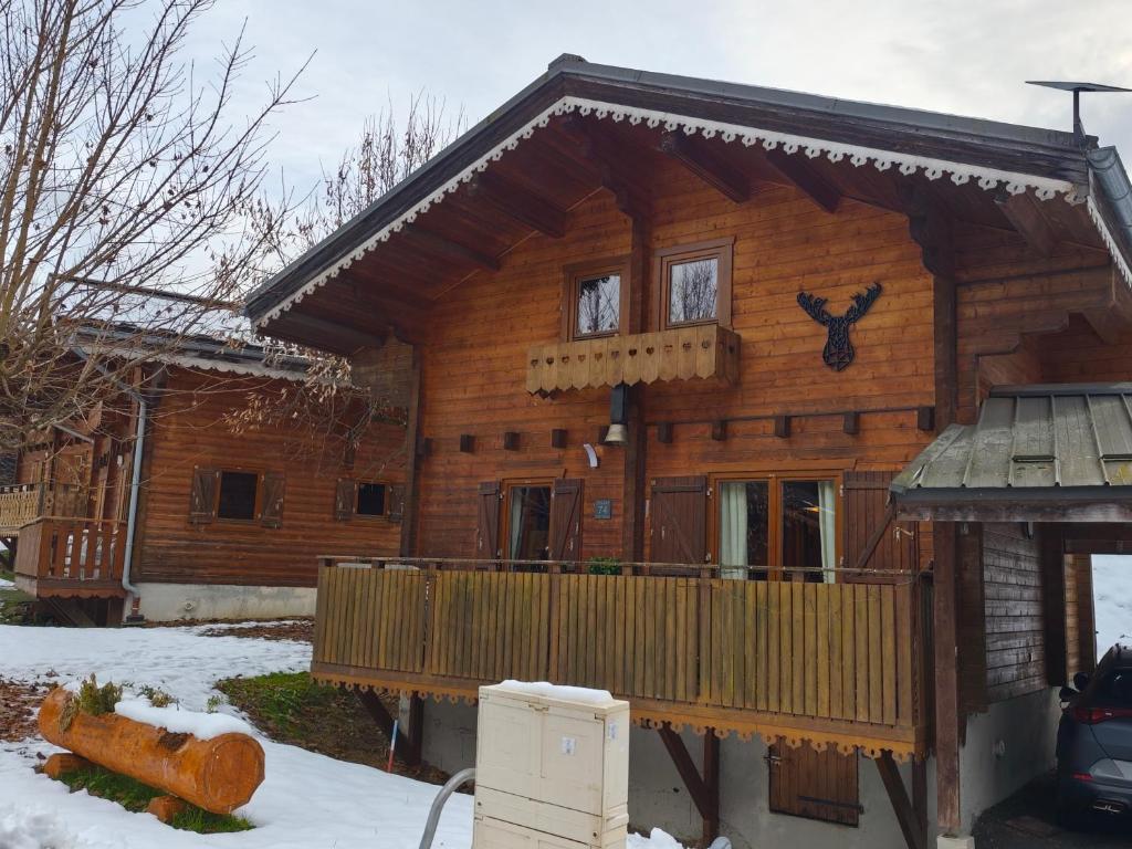 una baita di tronchi con veranda nella neve di Châlet CARIBOU 74 avec Piscine Chauffée a Morillon