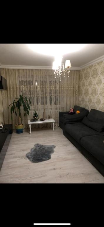 een woonkamer met een zwarte bank en een tafel bij se da in chirie apartament in Chişinău