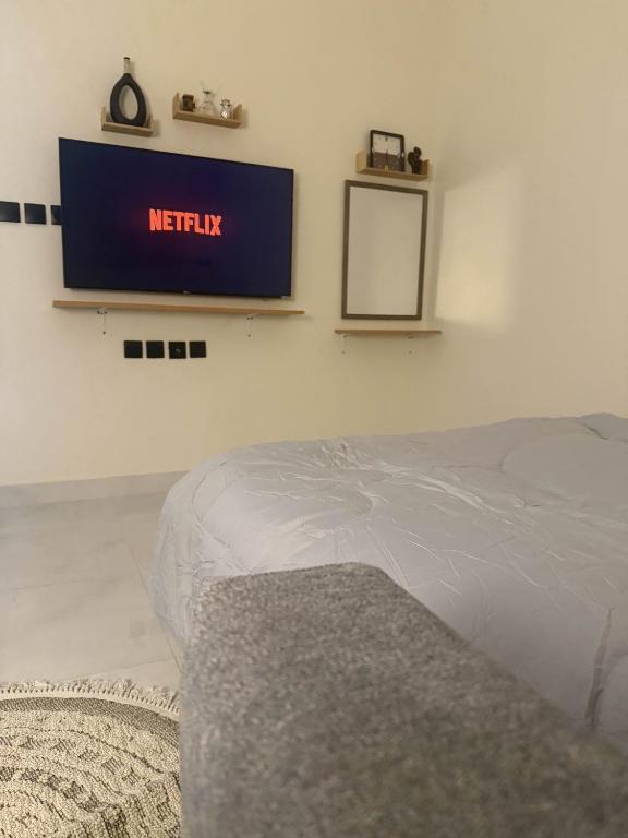 een slaapkamer met een bed en een tv aan de muur bij استديو بجلسة بمطبخ مستقل دخول ذاتي 12 in Buraydah
