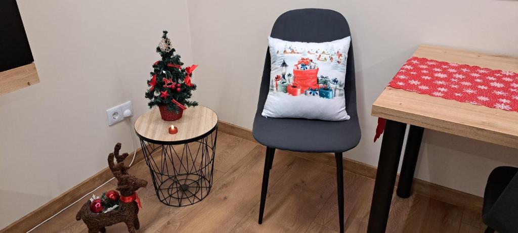 Una silla con una almohada navideña al lado de una mesa. en Emily Apartman Salgótarján, en Salgótarján