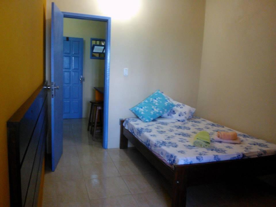 Dormitorio pequeño con cama con almohadas azules en Apartamentos da Coló, en Arembepe