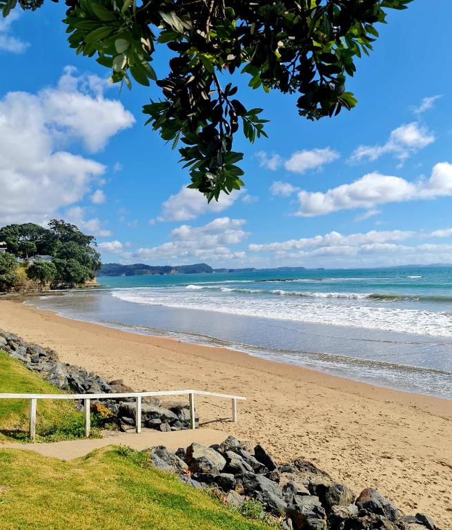 a beach with a white bench on the sand at Kiwi Classic in Red Beach