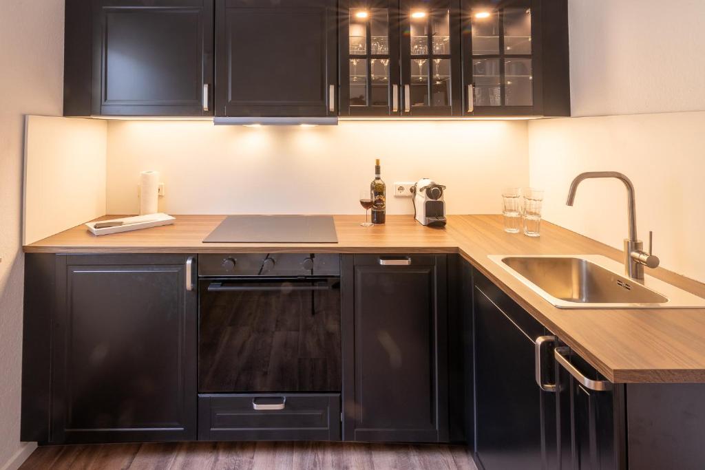 a kitchen with black cabinets and a sink at Zweisam am Alaunpark 
