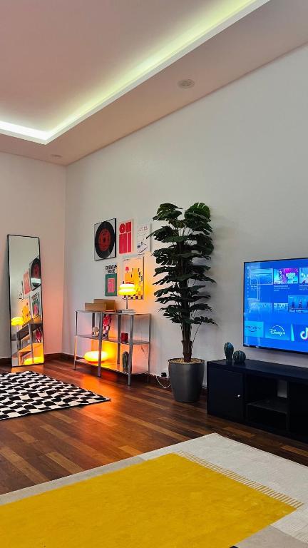 un soggiorno con TV e pianta in vaso di شقق ميد كانتري a Khamis Mushayt