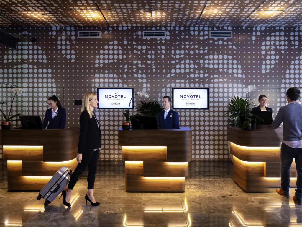 a woman walking through a lobby with luggage at Novotel Brisbane South Bank in Brisbane