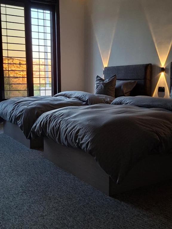 zwei Betten in einem Schlafzimmer mit zwei großen Fenstern in der Unterkunft Jeeso Hotel in Gerasa