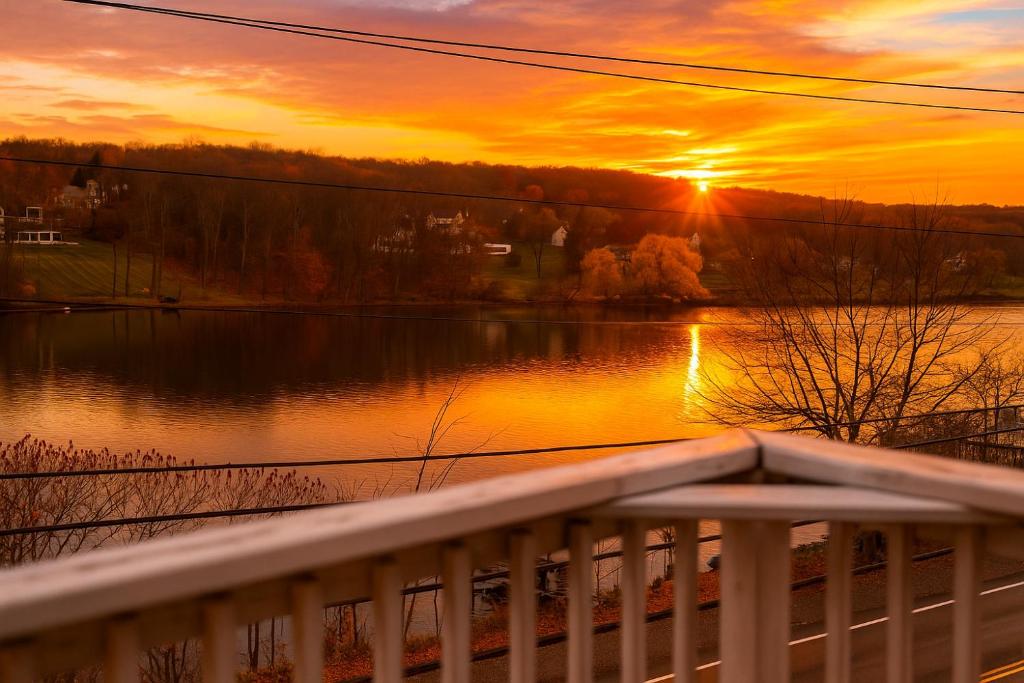 a sunset over a body of water with a white railing at Modern Lakeview Escape | Scenic Deck • Fire Pit in Monroe