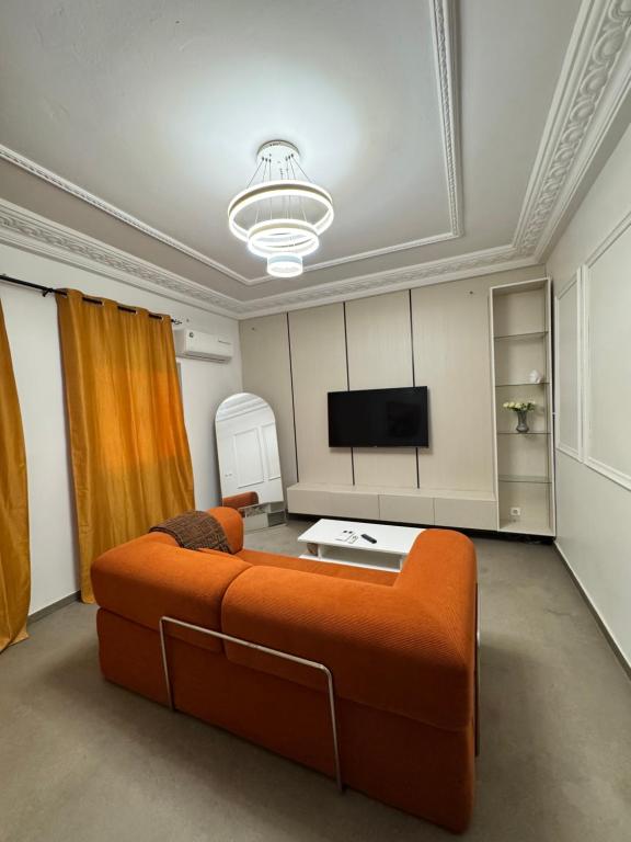ein Wohnzimmer mit einem orangenen Sofa und einem Flachbild-TV in der Unterkunft COZy APPARTE in Dakar