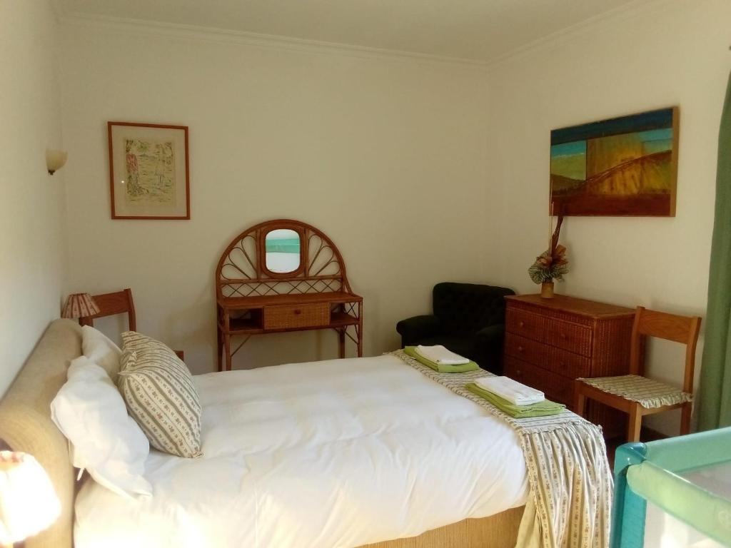 une chambre avec un lit blanc et une chaise dans l'établissement Casa das Oliveiras - Manteigas, à Manteigas