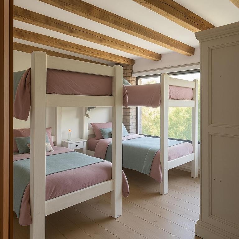 two bunk beds in a room with two windows at Beachfront house for 20 people in Vichuquén Lake