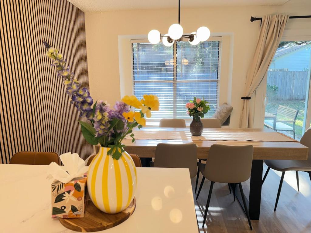 Modern and Cozy 3BR Retreat Perfect for Families or Big Group في سيدار بارك: غرفة طعام مع طاولة مع إناء من الزهور