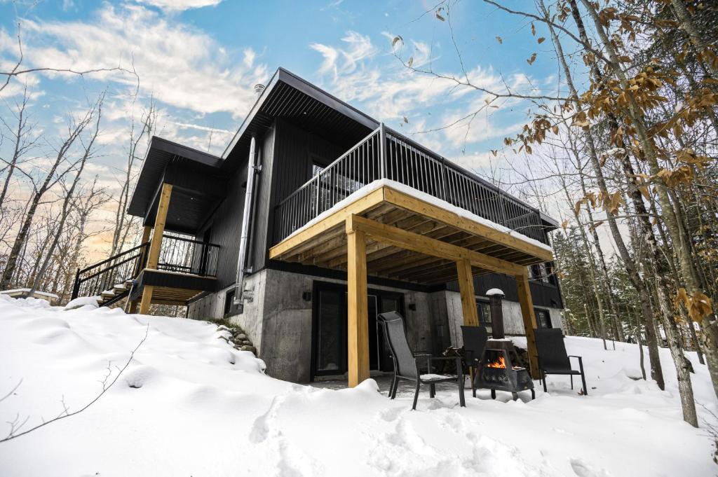 a house with a deck in the snow at Le 4 sur le lac, Accès au lac, Boisée, BBQ in Wentworth