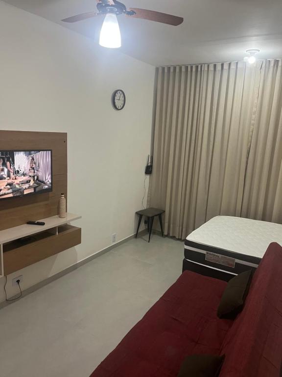 a living room with a bed and a tv at Kitnet Muriqui 2 in Mangaratiba