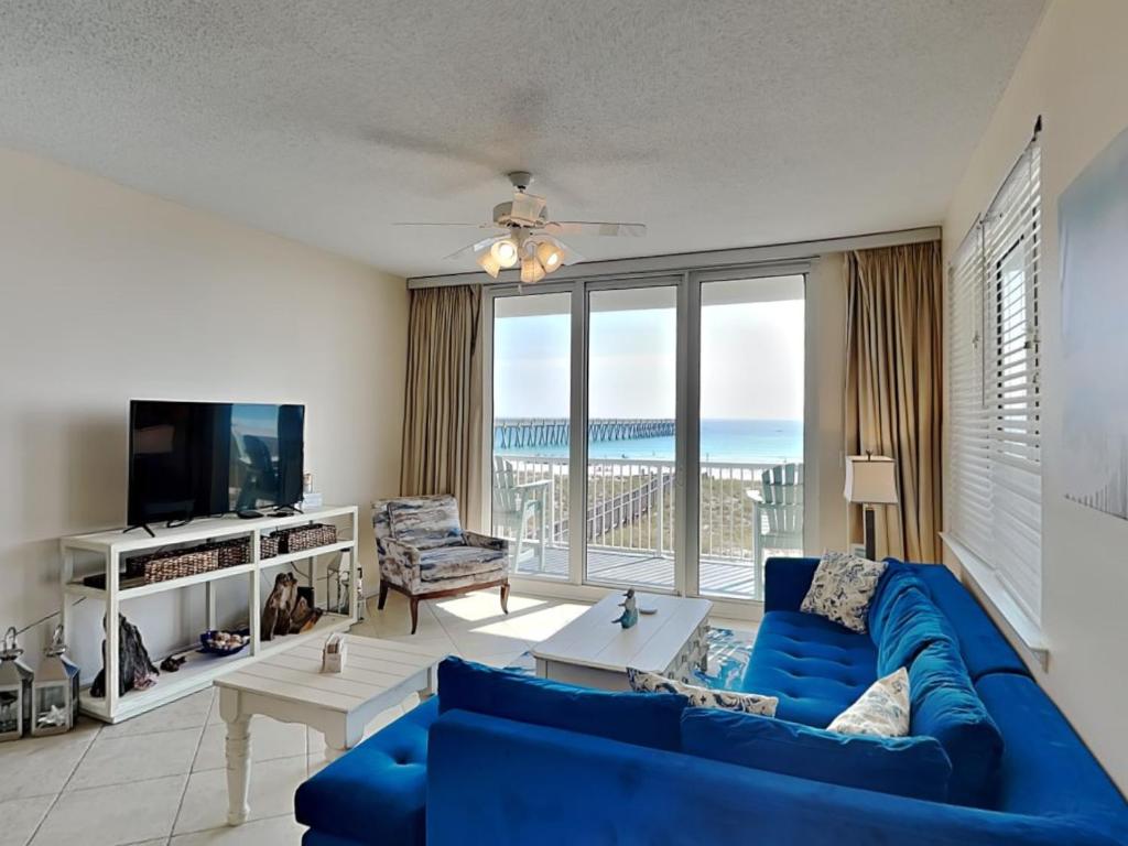 a living room with a blue couch and a view of the ocean at Summerwinds #204 in Navarre