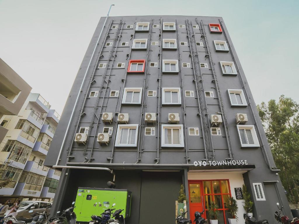 ein hohes graues Gebäude mit weißen Fenstern und Motorrädern in der Unterkunft Townhouse Sarjapur Near Bellandur in Bangalore