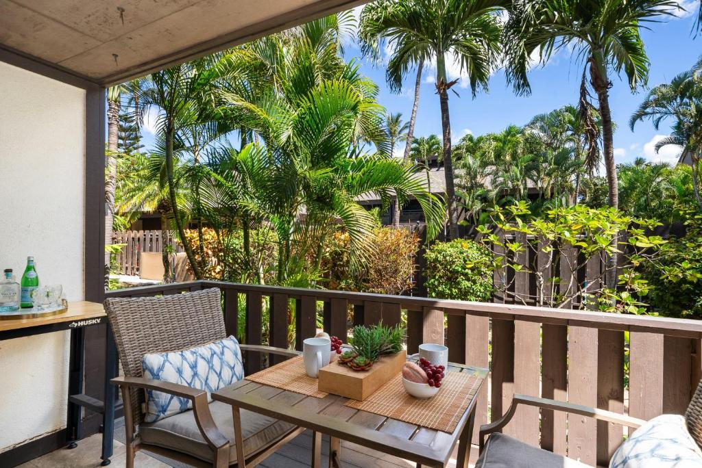 a patio with a table and chairs and palm trees at Kihei Resort 127 · KRS 127 Relaxing 1BD Condo w AC Pool Beach Ne in Kihei