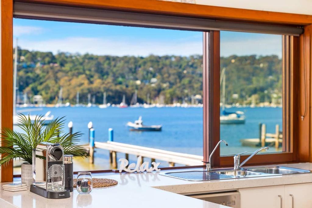 a kitchen window with a view of the water at Waterfront Scotland Island Holiday Home - Family & Pet Friendly - 3 Bedrooms - Wifi - Netflix - Private Jetty in Scotland Island