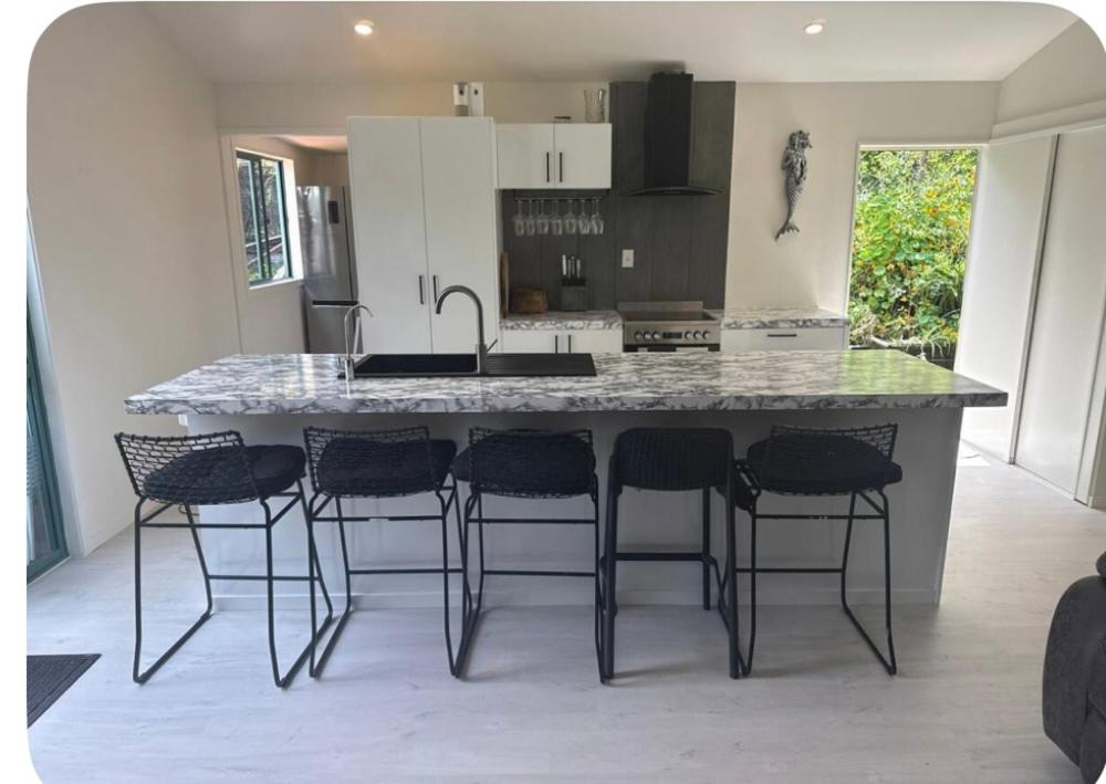 a kitchen with a large island with bar stools at Whangapoua retreat in Whangapoua