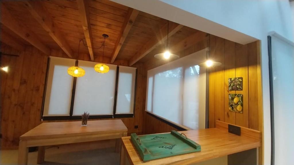 a room with a wooden table and some windows at Cabaña martita in San Martín de los Andes