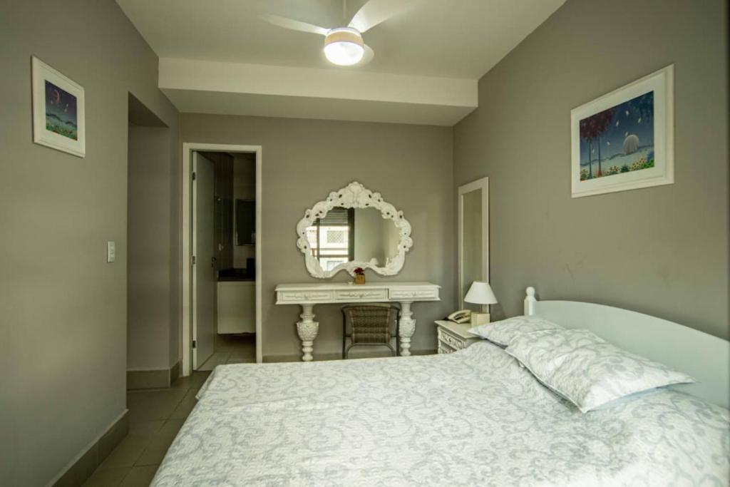 a bedroom with a white bed and a mirror at Apartamento Riviera na Praça das Artes Módulo 6 in Riviera de São Lourenço