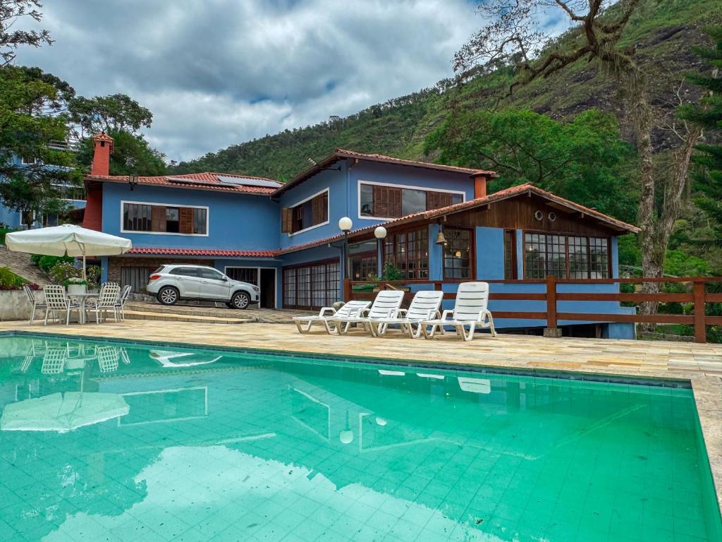 a house with a swimming pool in front of a house at Teresopolis casa ampla em clube com piscina in Teresópolis