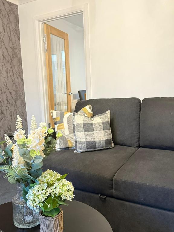 ein Wohnzimmer mit einem Sofa und Blumen auf dem Tisch in der Unterkunft Wigan 2-Bedroom Modern house - Cozy & Relaxing Stay in Bickershaw