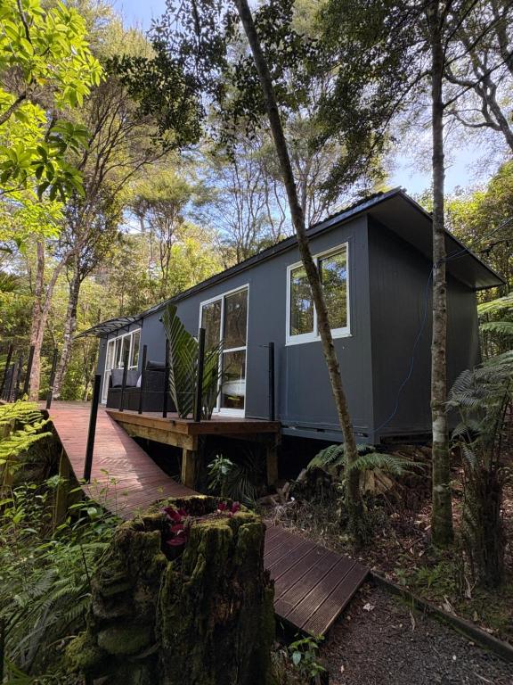 Una pequeña casa gris en el bosque en Tui Bush Chalet, en Parakakau