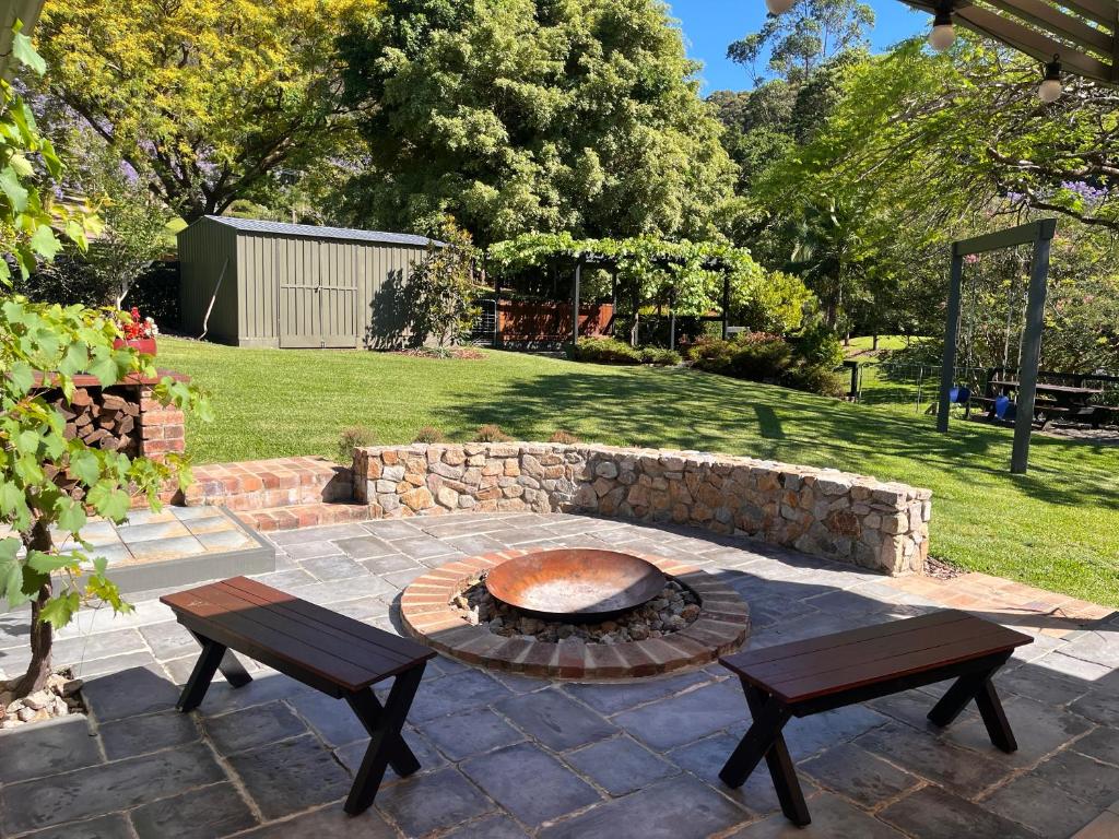 a patio with a fire pit and two benches at Cedarvale Cottage in Boambee