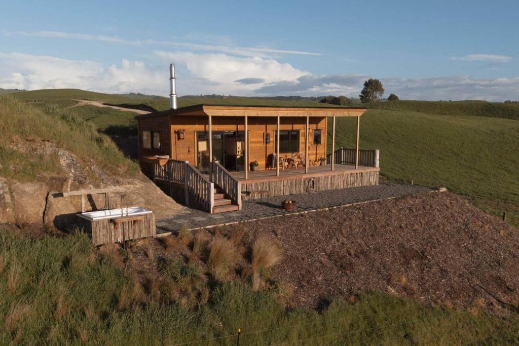 una casa en la cima de una colina en un campo en Sunsets, outdoor bath, mountain views, fire pit, en Marotiri