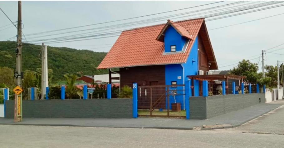 ein kleines blaues Gebäude mit rotem Dach in der Unterkunft Cabana do Embaú Experience in Palhoça