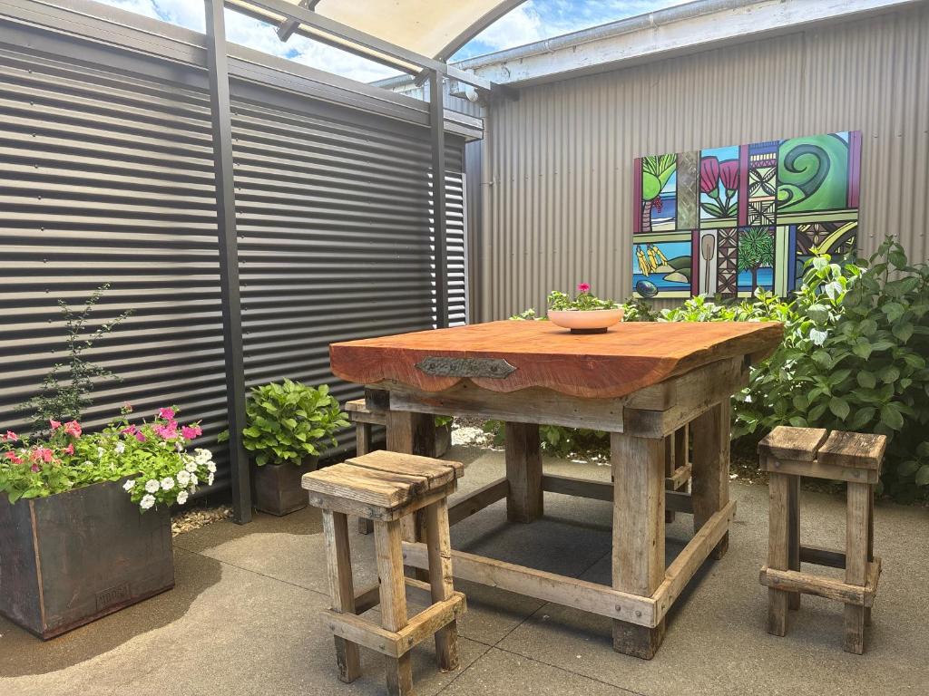 a wooden table and two stools in a garden at A Rural Retreat, Cabin with Private Bathroom No 2 in Hastings