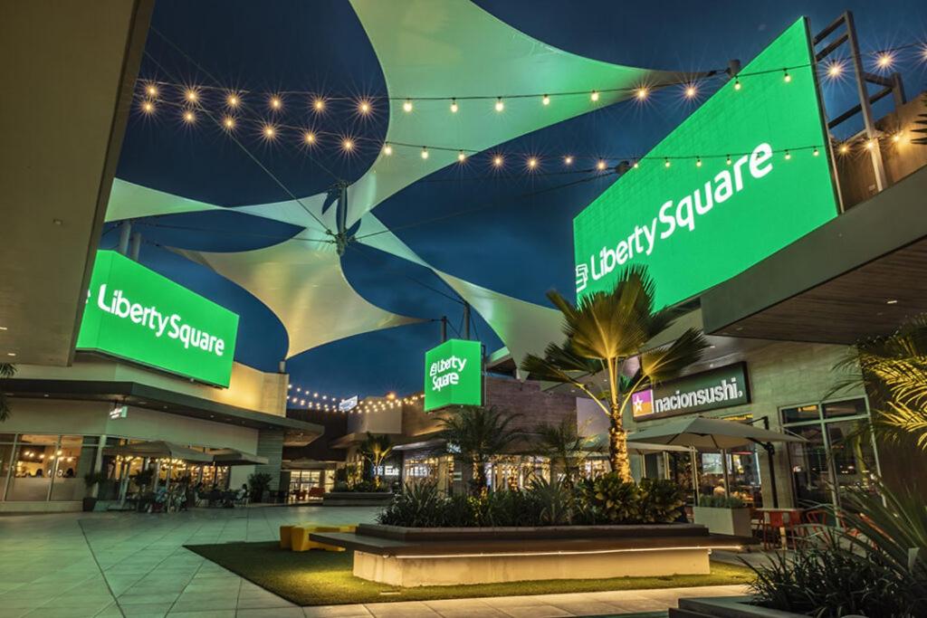 a shopping mall at night with green signs and lights at Puerta al Tren apartamento in San Juan