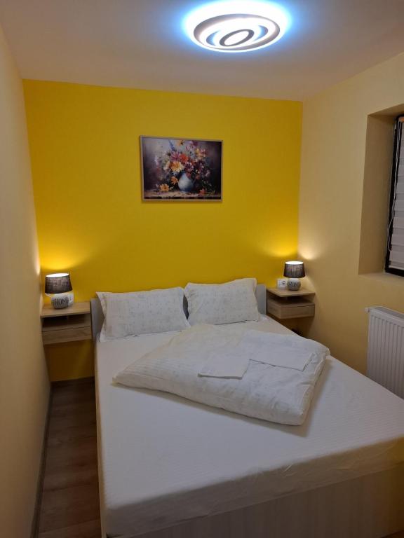 una camera con un letto bianco e una parete gialla di Popas La Vintu 