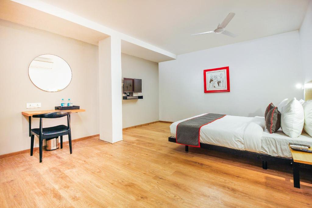 a bedroom with a bed and a desk and a table at Super Townhouse RCC Sunrise in Hyderabad