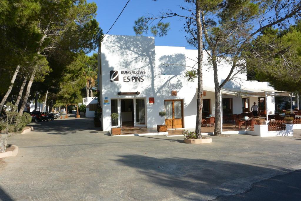 un edificio blanco con un cartel en el costado en Bungalows Es Pins - Emar Hotels en Playa Migjorn