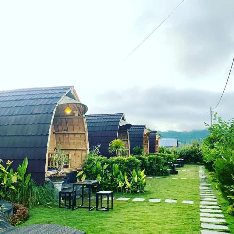 a row of huts in a yard with grass at Tegal Bamboo Cottages & Private Hot Spring in Baturaja