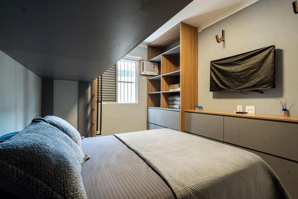 a bedroom with a bed and a tv on the wall at Seu apê de férias - Praia Grande in Praia Grande