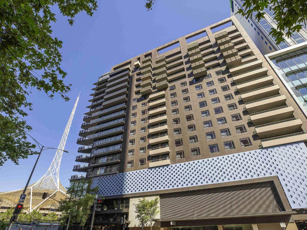 Un edificio alto de apartamentos con una grúa al fondo. en Mantra Southbank, en Melbourne