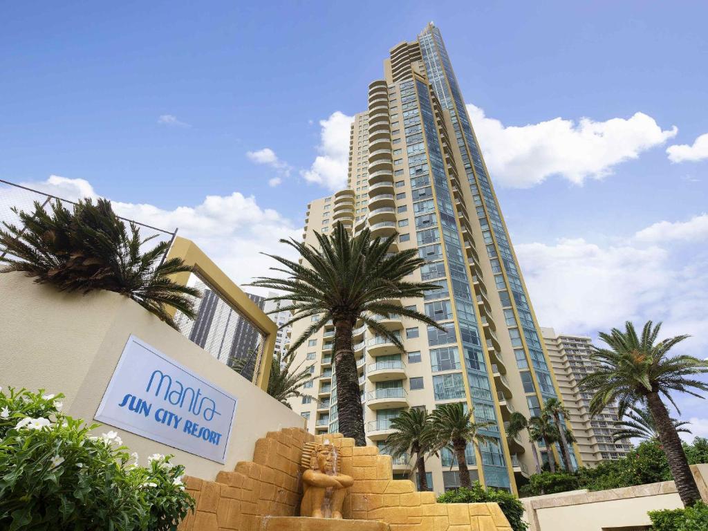Un gran edificio con palmeras delante. en Mantra Sun City, en Gold Coast