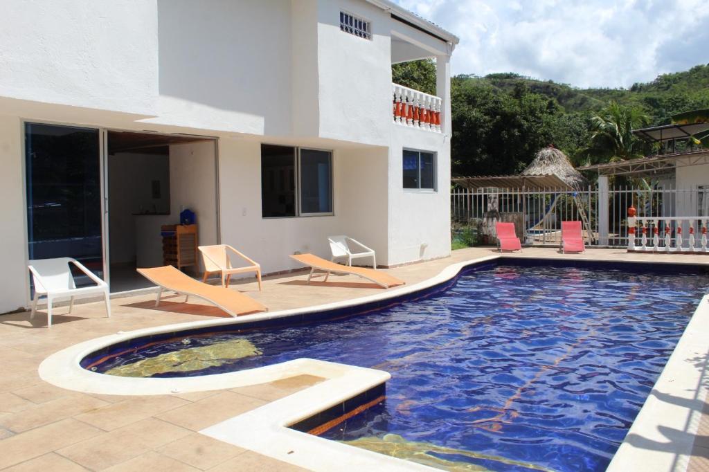 a swimming pool with chairs and a house at Casa moderna con piscina privada, Jacuzzi, Melgar Tolima in Melgar