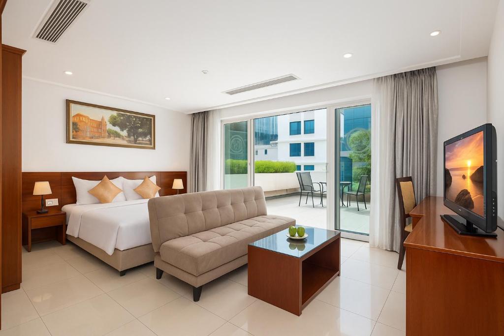 ein Hotelzimmer mit einem Bett, einer Couch und einem Fernseher in der Unterkunft White Lotus Hotel Saigon in Ho-Chi-Minh-Stadt
