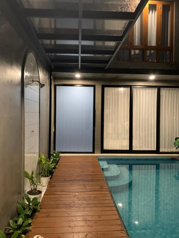 a swimming pool with a wooden walkway next to a building at Alena Villa Private Pool in Blimbing