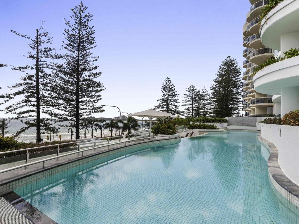 a large swimming pool next to a building at Mantra Sirocco in Mooloolaba