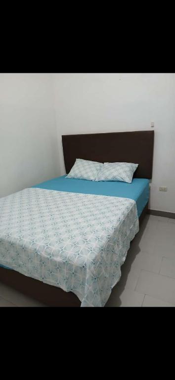 a bedroom with a bed with a blue comforter at Hotel Perezoso in Iquitos
