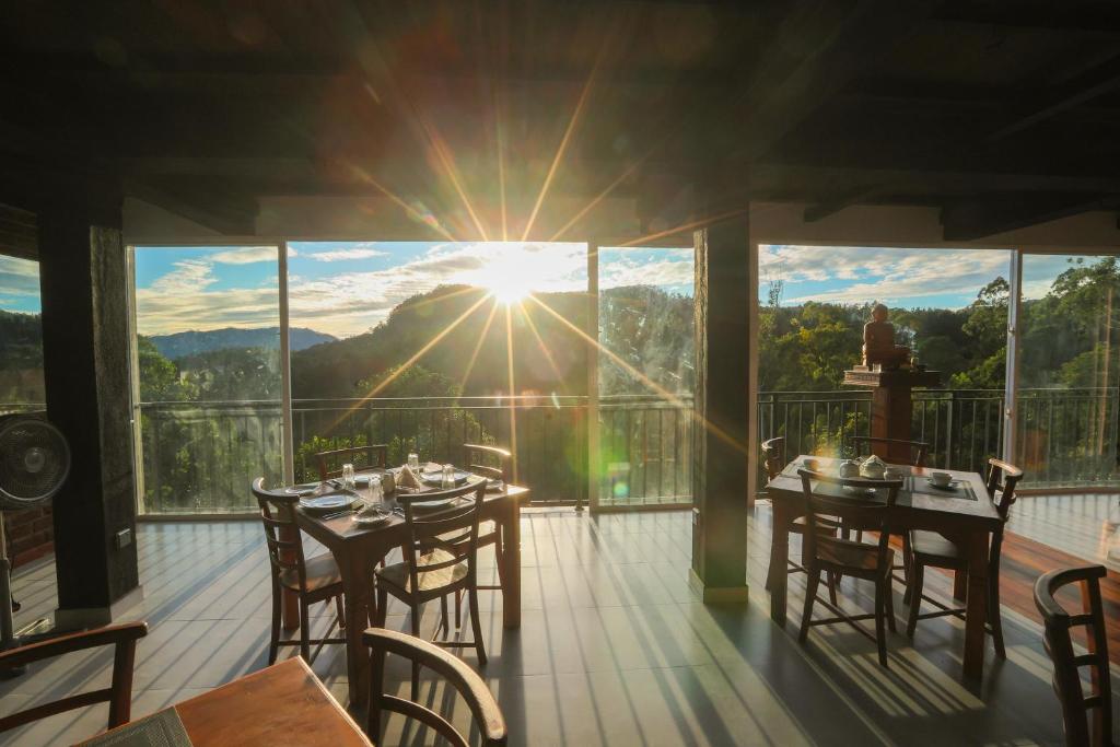 a patio with tables and chairs on a balcony with the sun shining at Ivory Canopy Resort - Ella in Ella