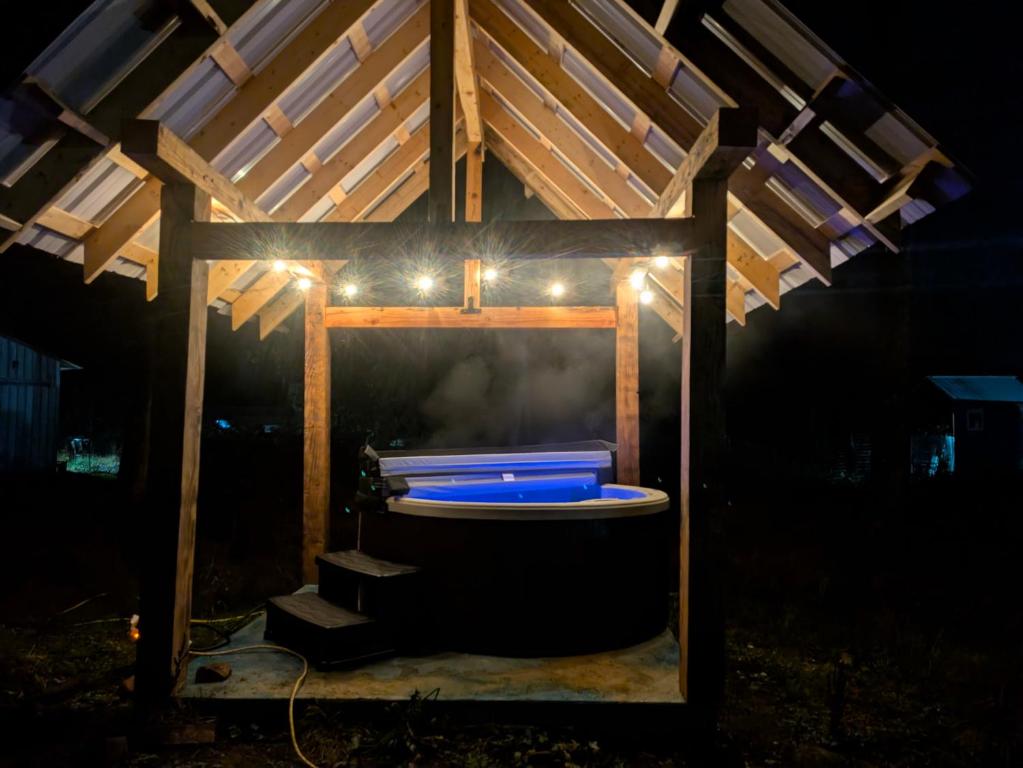 un gazebo in legno con vasca da bagno con luci di Farmhouse cabin on 33 acre farm a Powell River