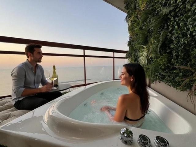 a man and a woman sitting in a bath tub at קו המים-סוויטה עם גקוזי במרפסת על הטיילת! in Netanya
