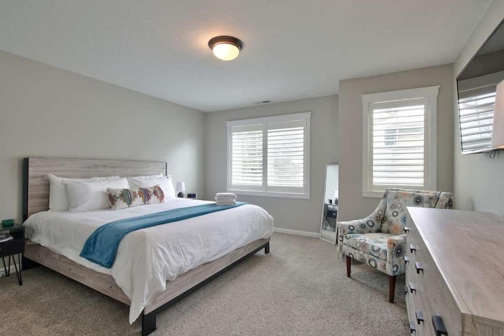 CarltonAdventure Awaits - Wine country oasis w Cozy deck的一间卧室，里面有一张床、一把椅子和几扇窗户。