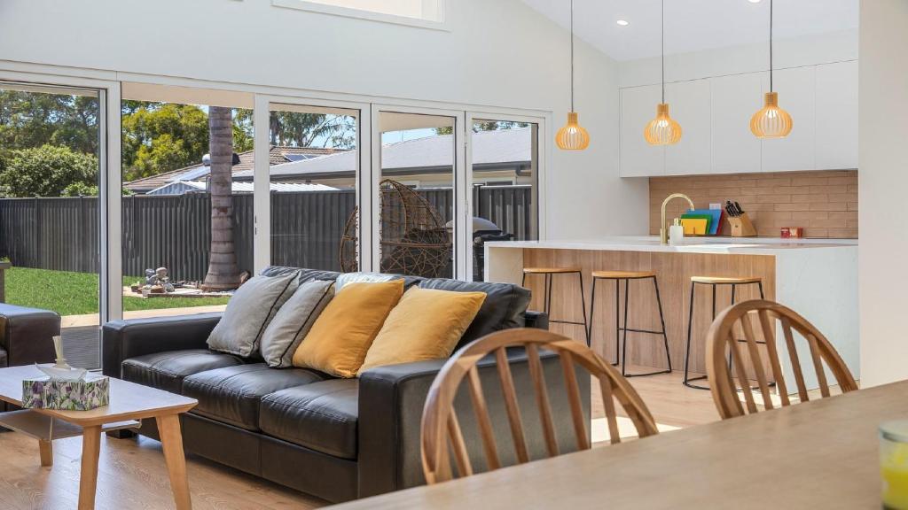 ein Wohnzimmer mit einer schwarzen Couch und einer Küche in der Unterkunft Luxe Hideaway - South Umina in Umina